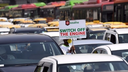 志工手持「熄火」標語，於紅燈時穿梭新德里的車道上。