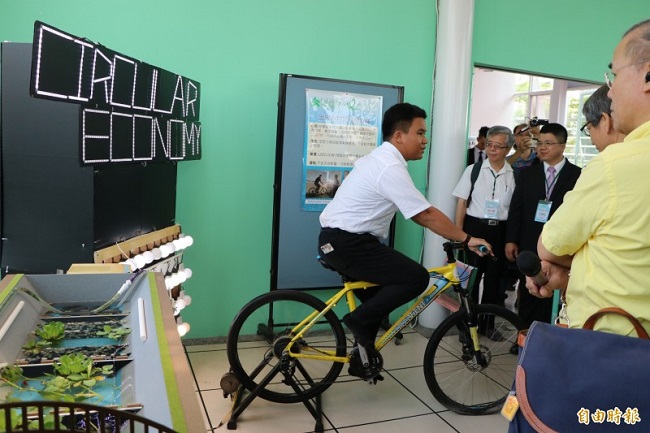 實踐基地總部展示校內師生相關綠能作品，學生親自示範《磁助力創能踩踏車》。（記者萬于甄攝）